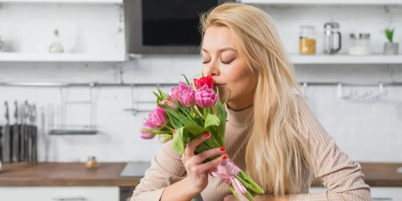 mujer oliendo unas flores
