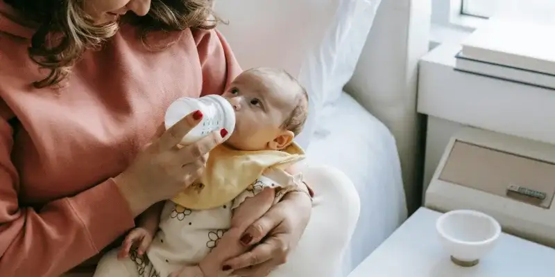 madre dando biberón a bebé